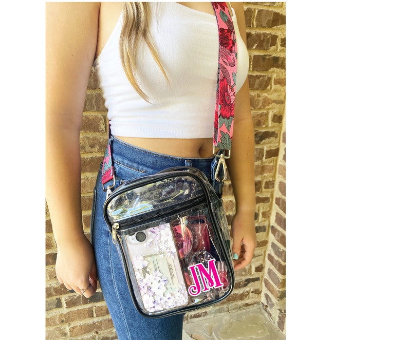 Clear stadium bag for women. Clear stadium purse shown in black with pink floral shoulder strap and custom monogram in permanent vinyl. College girl wearing stadium approved crossbody bag.