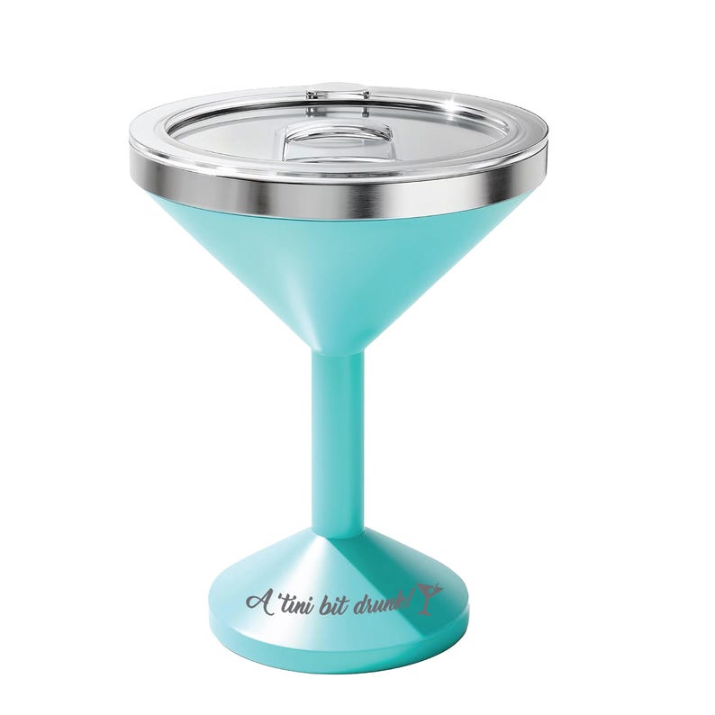 May include: A turquoise martini-shaped tumbler with a clear lid and a silver-toned rim. The base features the text A 'tini bit drunk! with a small martini glass icon. The vessel has a wide bowl, a slender stem, and a circular pedestal base.