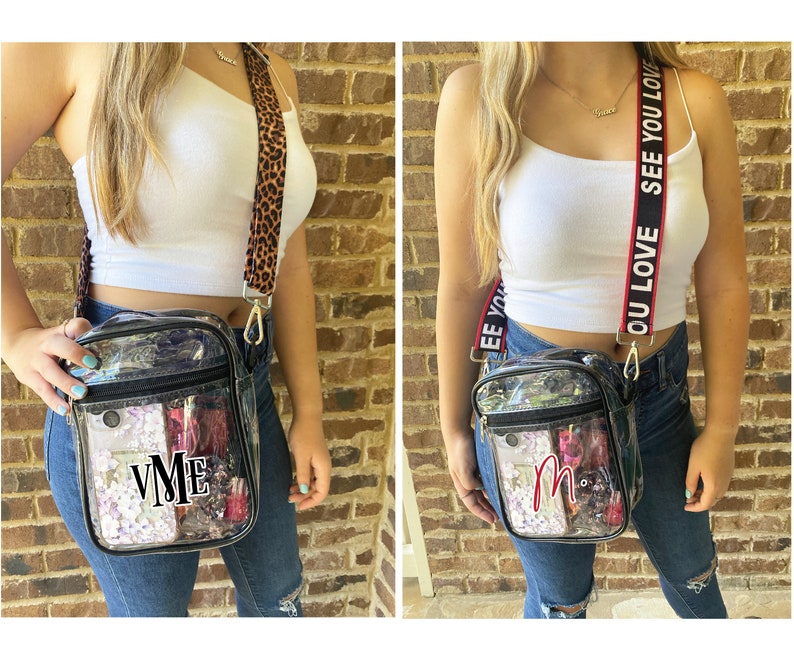 May include: Two clear plastic crossbody bags with different straps. One bag has a leopard print strap and the other has a red and white strap with the text "OU LOVE SEE YOU LOVE". Both bags have black trim and a zipper closure. The bag on the left has the initials "VME" in black letters on the front. The bag on the right has the initial "M" in red letters on the front.