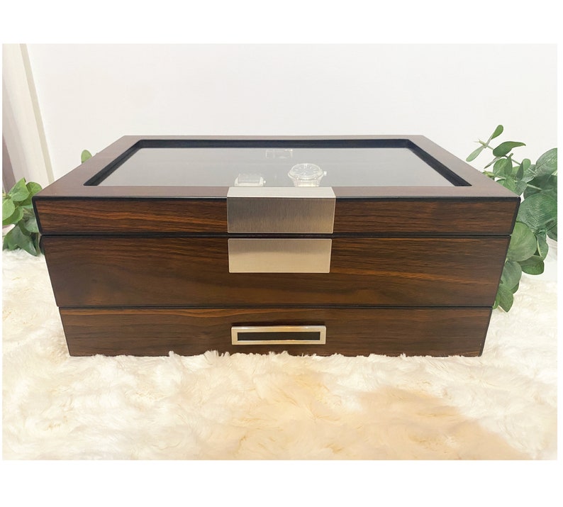 Front center view of walnut woodgrain watch display case. This watch box features slots with pillows to store and display 12 watches. Below display compartment is a valet drawer to organize mens accessories like cuff links, tie bars, collar stays