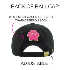 May include: Black baseball cap with an adjustable strap and a pink paw print on the back. The cap has space for 1-2 characters on the back.