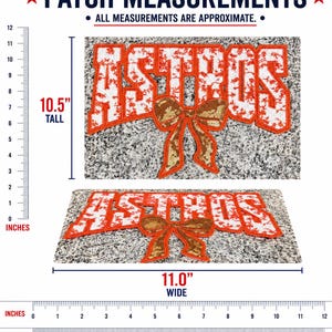 May include: An Astros patch featuring white letters with a red outline and a gold sequined bow. The patch measures 10.5 inches tall and 11.0 inches wide as indicated by the included rulers. The text reads ASTROS in a bold, block font style.