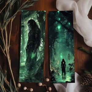 May include: Two fantasy-themed bookmarks. One depicts a figure in a dark forest with green accents. The other shows a silhouetted figure in a glowing green forest with hanging lanterns. The bookmarks are vertical and rectangular.