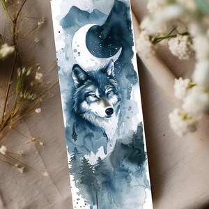May include: A watercolor bookmark featuring a wolf with a crescent moon and starry sky. The design incorporates shades of blue and gray, with a forest scene at the bottom. The bookmark is a vertical rectangle.