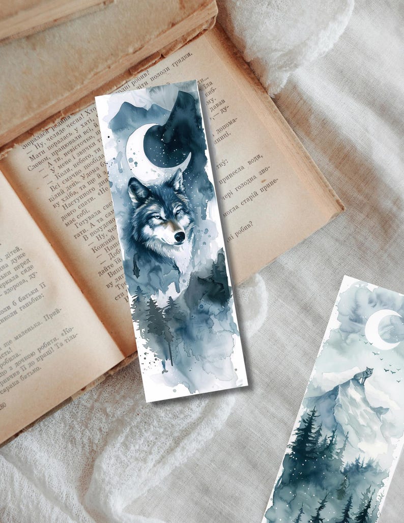 May include: Watercolor bookmarks featuring a wolf, mountains, and a crescent moon. The bookmarks have a blue and gray color scheme with a forest scene. The artwork is on a white background.