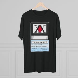 May include: Black t-shirt featuring a graphic design. The design includes a white rectangle with the letters "XX" and a red diamond shape. Below the rectangle is a blue rectangle with text.