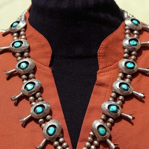 May include: A silver and turquoise necklace with a traditional Native American design. The necklace features multiple oval-shaped turquoise stones set in silver, with decorative silver accents.
