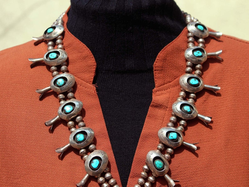 May include: A silver and turquoise necklace with a traditional Native American design. The necklace features multiple oval-shaped turquoise stones set in silver, with decorative silver accents.
