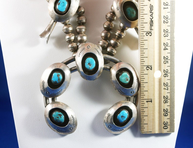 May include: A silver and turquoise necklace with a horseshoe pendant. The pendant has five turquoise stones set in silver. The necklace is 28 inches (71 cm) long.