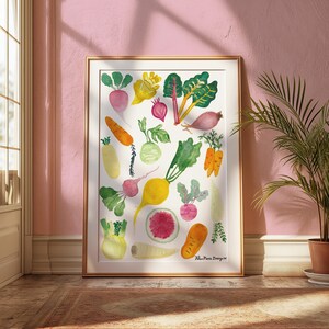 Pode incluir: Uma impressão em aguarela emoldurada apresentando uma coleção de vegetais coloridos, incluindo cenouras, rabanetes, beterrabas e folhas verdes, dispostos sobre um fundo branco. O texto Helen Marie Design Co. está impresso no canto inferior direito.