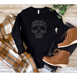 Puede incluir: Camiseta negra de manga larga con un gráfico de calavera y el texto "Fentanyl Awareness Help Save The Silent Pandemic".