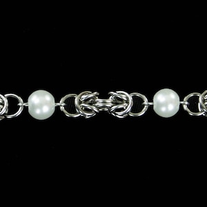 May include: A silver chain bracelet with two white pearl beads.