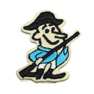 May include: Embroidered patch featuring a cartoon character in a tricorn hat, holding a rifle. The character is depicted in black, light blue, and white, with a cream-colored background. The patch is likely for clothing or accessories.