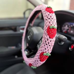 May include: Pink crocheted steering wheel cover with red embroidered strawberries.