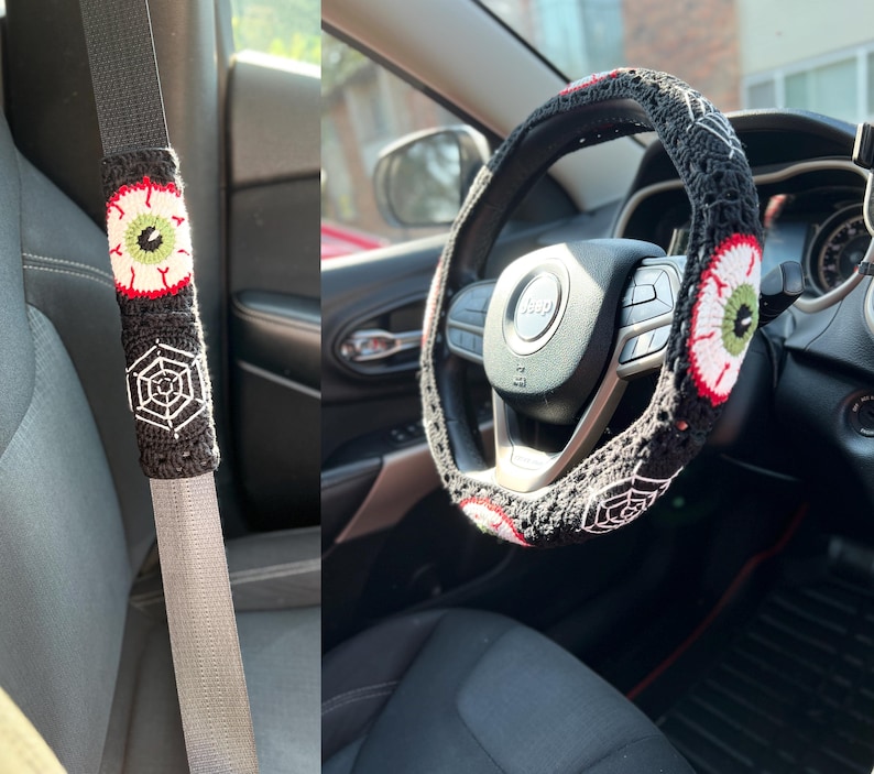 Op de afbeelding: Een zwart-witte gehaakte stuurwielhoes met een rood en groen oogontwerp. De hoes zit op een zwart stuurwiel met een zilveren Jeep-logo.