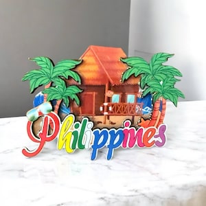 May include: A colorful wooden souvenir of the Philippines featuring a beach hut, palm trees, and the word "Philippines" in rainbow letters.