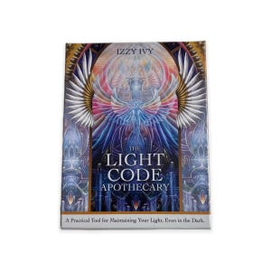May include: A deck of cards titled "The Light Code Apothecary" with a colorful illustration of an angel with outstretched wings. The text "Izzy Ivy" is at the top. The bottom text reads "A Practical Tool for Maintaining Your Light, Even in the Dark."