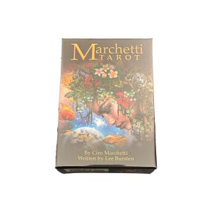 May include: A box for a tarot deck with a colorful image of a woman with flowers in her hair and fish swimming around her. The text on the box reads "Marchetti Tarot" and "By Ciro Marchetti. Written by Lee Bursten."