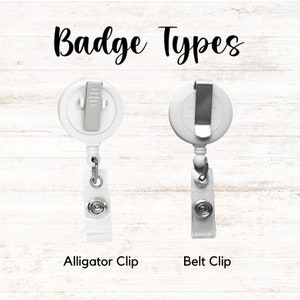 Op de afbeelding: Twee witte badgehaspels met verschillende clipstijlen. De linkerhaspel heeft een alligatorclip en de rechterhaspel heeft een riemclip. De tekst "Badge Types" staat in cursief bovenaan en de tekst "Alligator Clip" en "Belt Clip" onderaan.
