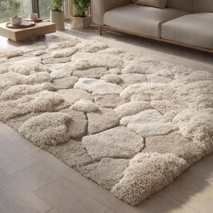 May include: A beige area rug with a stone-like pattern. The rug features varying shades of beige and cream, creating a textured, three-dimensional effect. The rug is rectangular and appears to be made of a soft, plush material.