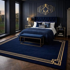 May include: A luxurious bedroom with a navy blue color scheme. The room features a large bed with a tufted headboard, a navy blue rug with gold trim, and a gold geometric wall art piece. The room is decorated with gold accents and a bench at the foot of the bed.