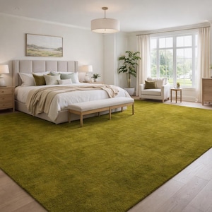 May include: A bright, spacious bedroom with a large, lime green rug covering most of the floor. The room features a bed with a beige headboard, a bench, and two nightstands. A large window and a dresser are also visible.