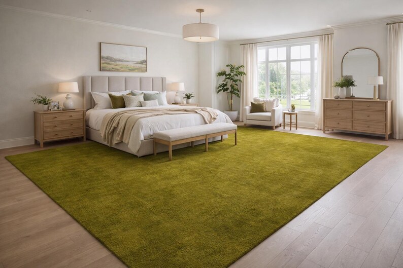 May include: A bright, spacious bedroom with a large, lime green rug covering most of the floor. The room features a bed with a beige headboard, a bench, and two nightstands. A large window and a dresser are also visible.