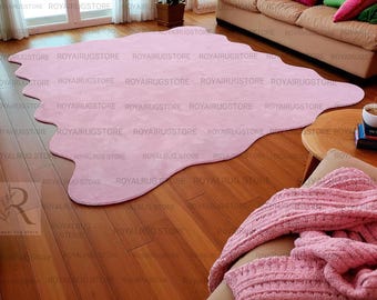 Puede incluir: Una alfombra rosa grande, de forma irregular, sobre un suelo de madera. La alfombra tiene una textura suave y un diseño único. La habitación tiene una paleta de colores neutros, con un sofá y una mesa de centro.