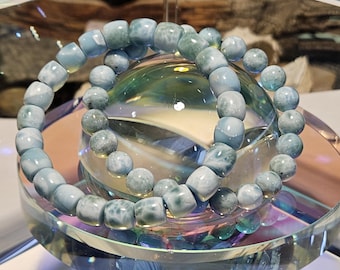 May include: Two blue and green gemstone bracelets with a swirling pattern. The bracelets are made of round beads and are stacked on top of each other.