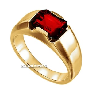 Puede incluir: Un anillo dorado con una gema rectangular de color rojo intenso. El anillo tiene una banda lisa y pulida y un engaste que sujeta la gema de forma segura. El texto "uniquejewelin" es visible en el anillo.
