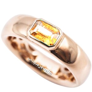 Puede incluir: Un anillo de oro con una sola piedra preciosa rectangular amarilla engastada en el centro. El anillo está grabado con el texto "uniquejewel.in".
