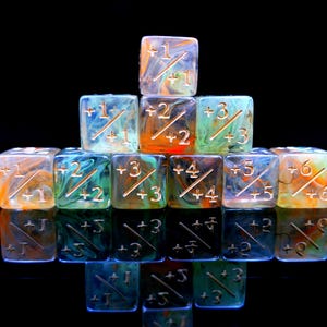 May include: A pyramid of twelve multi-colored dice with gold-colored numbers and symbols. The dice are translucent with swirls of orange, blue, and green. Each die has a different number from +1 to +6.