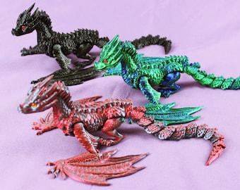 May include: Three articulated dragon figurines, one black, one green, and one red. The dragons have detailed scales and wings.