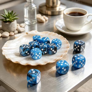 Könnte beinhalten: Ein Set aus zwölf sechsseitigen Würfeln mit einem marmorierten blau-schwarzen Wirbelmuster und weißen Augen. Neun Würfel liegen in einer großen, natürlichen Jakobsmuschelschale, während drei weitere Würfel daneben auf der Oberfläche platziert sind.