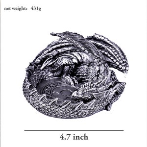 May include: A silver dragon figurine curled up in a sleeping position. The dragon is detailed with scales and has a textured surface. The dragon is 4.7 inches in diameter.