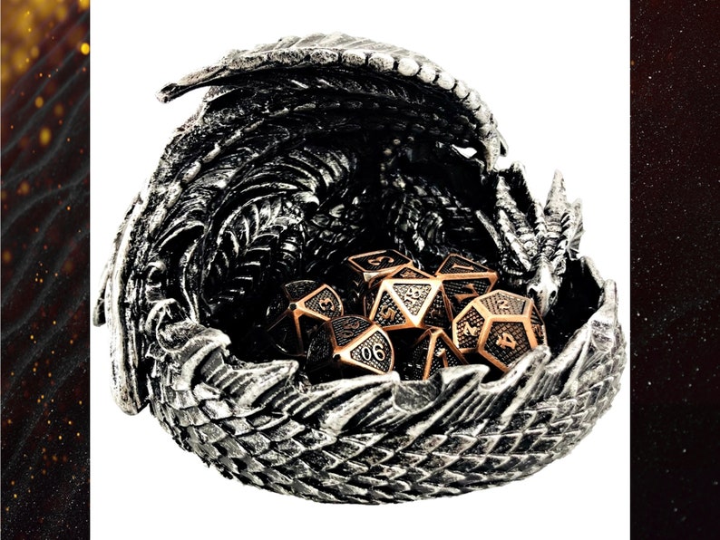 May include: A silver dragon sculpture with an open mouth, holding a set of copper and silver dice. The dragon is a dice tray for tabletop games.