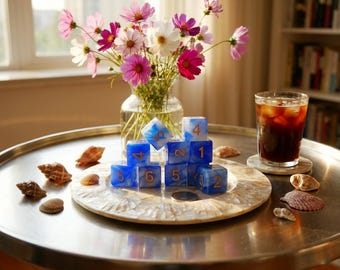 May include: A set of blue and white marbled polyhedral dice with gold-colored numbers arranged in a stack on a round, shell-inlaid tray. The dice feature various numerical values including 1, 2, 4, 5, and 6 clearly visible on their faces.