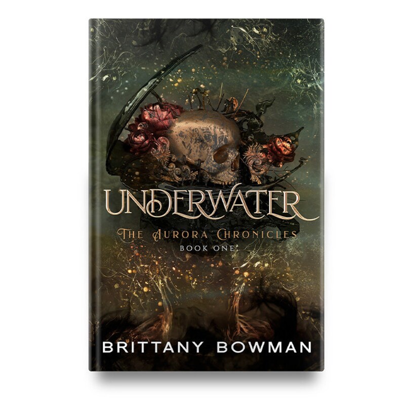 May include: Book cover with a skull adorned with red roses and a dark green background. The title "UNDERWATER" is in gold lettering with the subtitle "The Aurora Chronicles Book One" in smaller gold lettering. The author's name "BRITTANY BOWMAN" is at the bottom of the cover in white lettering.