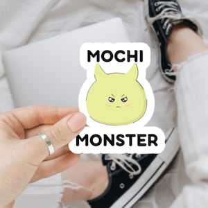 May include: A white sticker with black text that reads "Mochi Monster". The sticker features a cartoon illustration of a yellow mochi with horns and an angry expression.