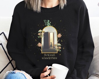 Op de afbeelding: Zwart sweatshirt met een afbeelding van een fee, een deur en paddenstoelen. De tekst "fictional wanderlust" staat onder de afbeelding.