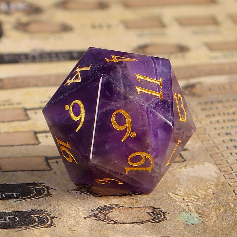 May include: A purple, faceted, gemstone dice with gold numbers. The numbers on the dice are 4, 9, 11, 13, 16, and 19.