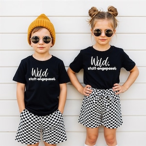 Könnte beinhalten: Eine weiße Keramiktasse mit schwarzem Henkel und dem Text "But First, Coffee" in schwarzer, handschriftlicher Schrift. Die Tasse steht auf einer weißen Oberfläche.