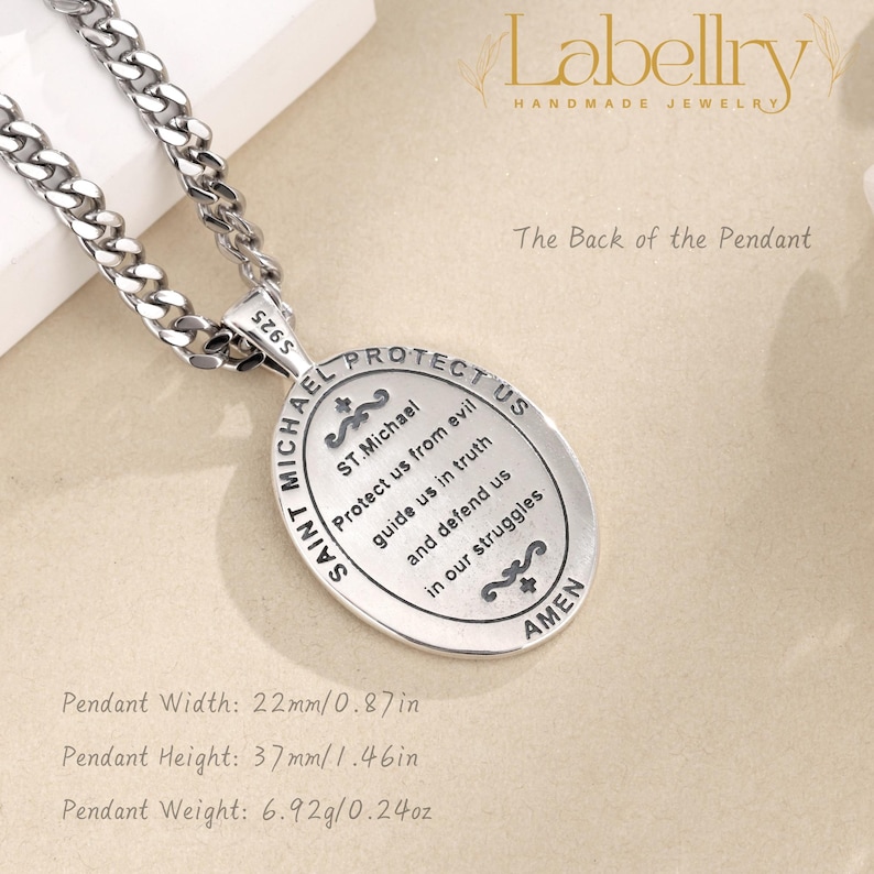 Pu&ograve; includere: Una collana con pendente di San Michele argentato. Il pendente ovale, largo 22 mm e alto 37 mm, presenta la scritta "SAINT MICHAEL PROTECT US" e una preghiera. La collana ha una catena spessa.