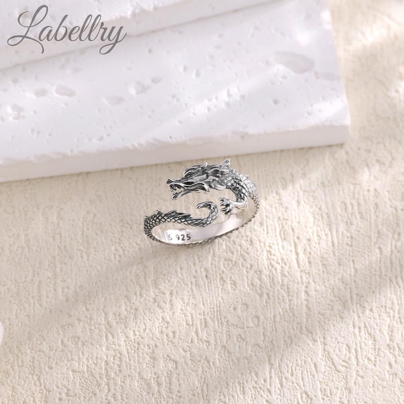 May include: Silver dragon ring with a detailed design. The ring is open and adjustable. The inscription "S 925" is visible on the band.