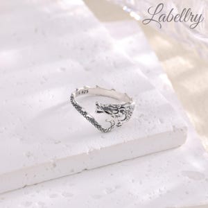 May include: Silver dragon ring with a detailed design. The ring is open on one side and has the inscription "S 925" on the inside.