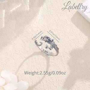 May include: Silver dragon ring with a textured finish. The ring is adjustable and measures 0.39 inches in diameter. The ring is marked with "S 925" and weighs 2.55 grams.