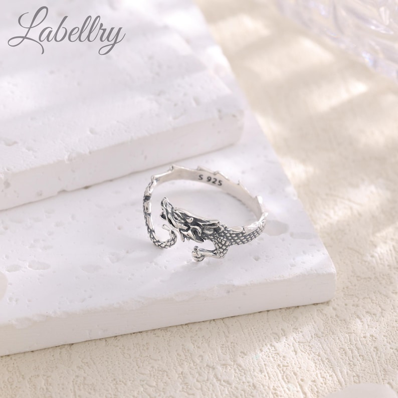 May include: A silver dragon ring with the inscription "S 925" on the band.
