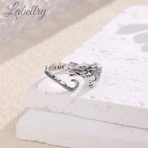 May include: Silver dragon ring with an open band. The ring is marked with "S 925" on the inside.