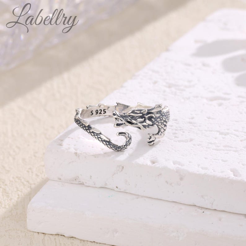 May include: Silver dragon ring with an open band. The ring is marked with "S 925" on the inside.