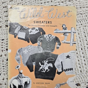 以下が含まれることがあります： ヴィンテージの「Wild West Sweaters」パターンブック。表紙には、カウボーイをテーマにしたセーター、馬に乗ったカウボーイ、リボルバーのイラストが描かれています。この本はGretchen Baum著で、4歳から12歳までの子供向けの編み方の説明が含まれています。
